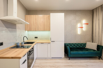 modern kitchen/living space with sleek cabinets, a green velvet sofa, and stylish lighting
