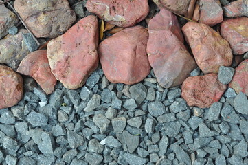 A pile of rocks and gravel with a red rock in the middle. The red rock is surrounded by grey rocks
