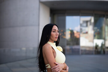 young woman in yello short dress walking on the street in the evening