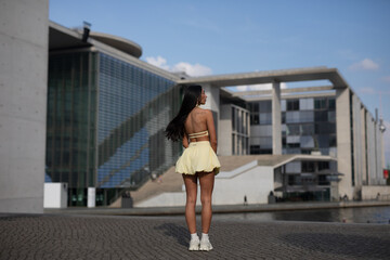 young woman in yello short dress walking on the street in the evening