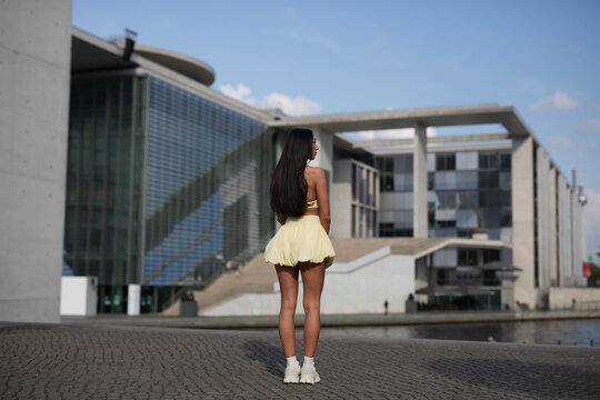 young woman in yello short dress walking on the street in the evening