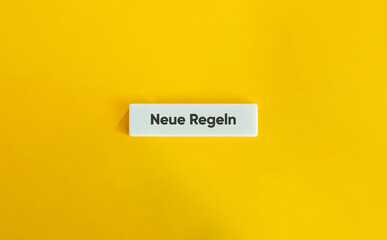 Neue Regeln Text auf weißem Kachelbanner vor gelbem Hintergrund