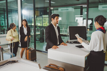 Business traveler checking in with passport while others wait in line at airport counter