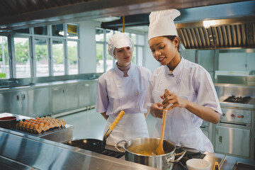 Group of culinary students practicing cooking skills with fresh ingredients in training kitchen school