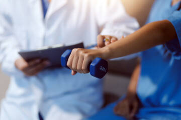 Unrecognizable uses blue hand weight during physical therapy session