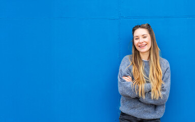 Obraz premium woman standing against blue wall with arms crossed