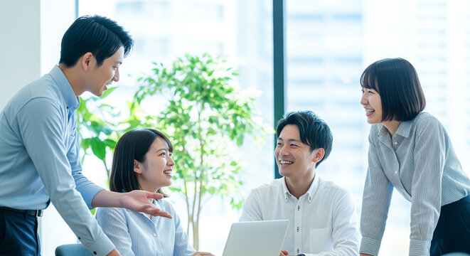 オフィスでノートパソコンを前に笑顔で打ち合わせをする4人の日本人会社員たちのビジネスミーティング