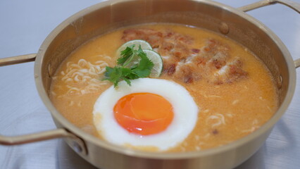 Curry instant noodles with katsu chicken and sunny egg in a golden aluminum pot