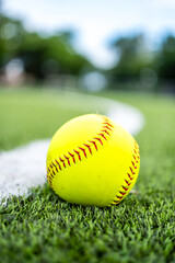 A vibrant neon yellow softball rests directly on a thick, On the Line: A Yellow Softball Poised for Action