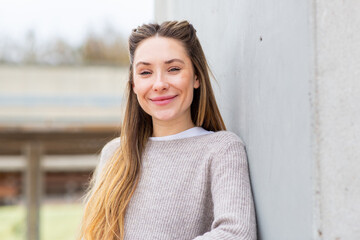 Smiling woman outdoors leaning against wall