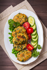 Chicken spinach burgers with green peas and vegetables on white plate. View from above, top studio shot
