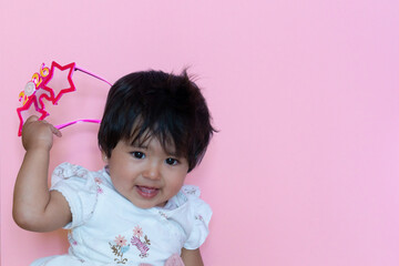 A smiling baby celebrates the arrival of the new year 2026, a happy girl wearing glasses from 2026. On a pink background.