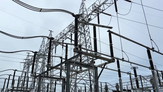 Disconnecting switch substation cloudy sky, high voltage power line and metal tower grid with ceramic insulator structure, industrial energy infrastructure and electricity transmission distribution