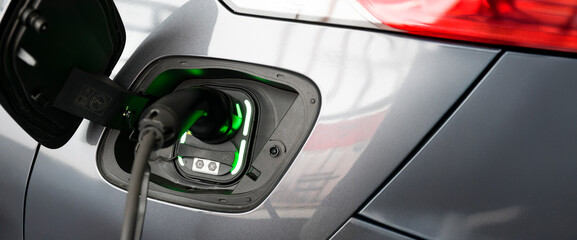 Electric car charging plug with glowing green indicator
