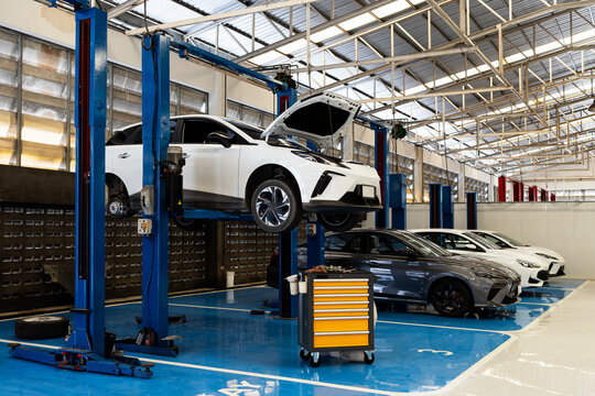 Electric car on hydraulic lift in modern auto repair workshop