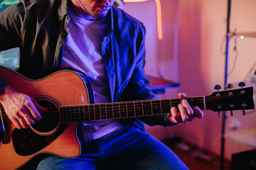 Musician composing music at home studio playing acoustic guitar
