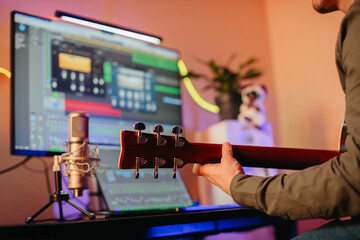 Musician composing music at home recording studio with guitar and computer