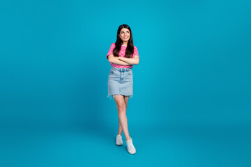 Young woman in casual summer outfit confidently poses against a solid blue background