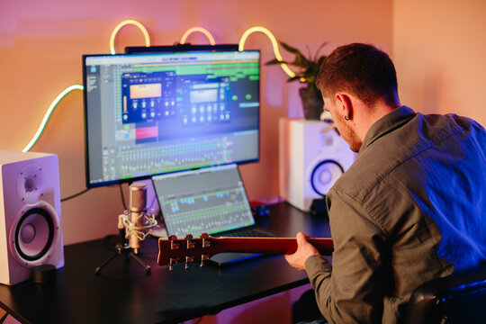 Musician composing music playing guitar and using computer software - Powered by Adobe