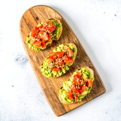Three avocado toast topped with tomatoes and a drizzle