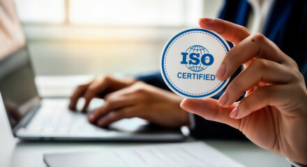 Iso certified concept, person holding a round stamp with iso certified text and globe icon, representing quality assurance and international standards