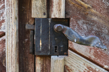 Close-up of an old metal handle on a wooden door