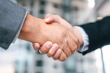 Two hands shake in a business setting, symbolizing agreement, partnership, and collaboration in a professional environment.