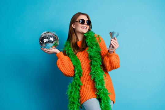 Beautiful young woman in casual fashion with a disco ball celebrating on a bright blue background - charming style - Powered by Adobe