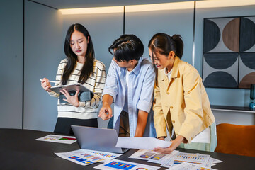 This dynamic asian business team people group working with paperwork standing at table, analyzing corporate strategy, reviewing plan, managing financial project overview at office meeting