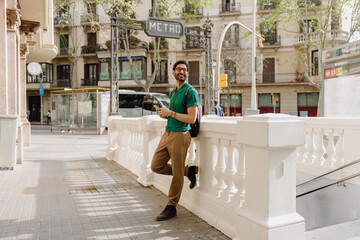 The man is smiling and looking away while holding the phone and leaning back