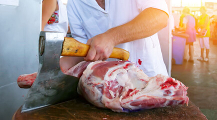 Butcher skillfully chopping meat in vibrant market during busy daytime hours