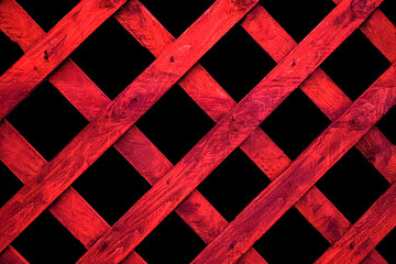 A garden trellis fence closeup in red on a black background