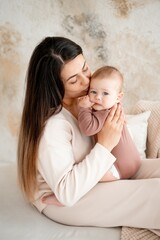 mom and baby, maternal love and care, a mother holds a baby in her arms, gently kissing and hugging him at home, a mother with a small child on maternity leave