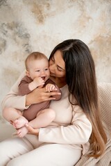 mom and baby, maternal love and care, a mother holds a baby in her arms, gently kissing and hugging him at home, a mother with a small child on maternity leave