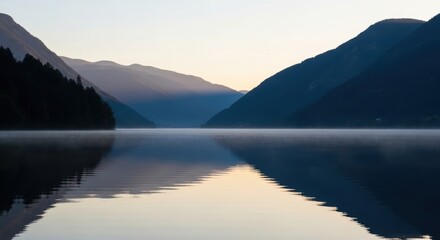 Serene mountain lake at dawn with reflections and misty hills