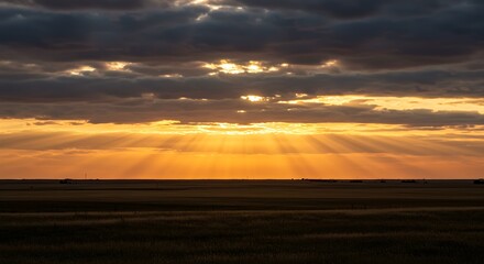 Sunset Sky with Golden Rays Breaking Through Dark Clouds Over Open Field
