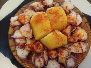 galician octopus with potatoes, paprika, salt and olive oil. typical Spanish Galician tapa, on a traditional wooden plate