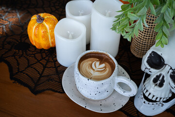 Halloween celebrated coffee,Close up of Hot coffee latte with latte art milk foam in cup mug with decor in a coffee a theme of halloween on wood desk Halloween holiday background.