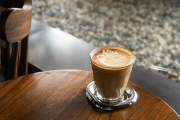 Hot coffee latte with latte art milk foam in cup mug on wood desk on top view. As breakfast In a coffee shop at the cafe,during business work concept,vintage style
