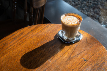 Hot coffee latte with latte art milk foam in cup mug on wood desk on top view. As breakfast In a coffee shop at the cafe,during business work concept,vintage style