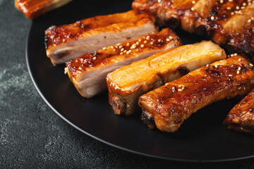 Hot grilled spare ribs from a summer BBQ served on a plate with sauce. Top view. Copy space
