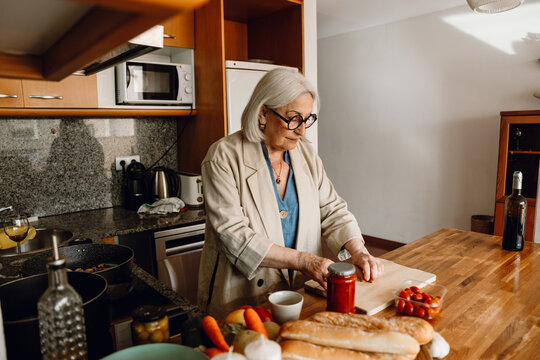 A woman puts her hands on a cutting board while standing in front of a table - Powered by Adobe