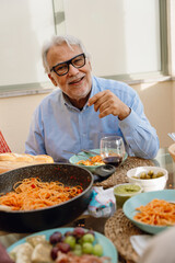 A man smiles while sitting at a table and looking ahead