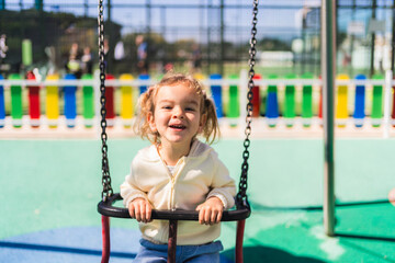 Smiling toddler enjoying a sunny day at the park, swinging and playing