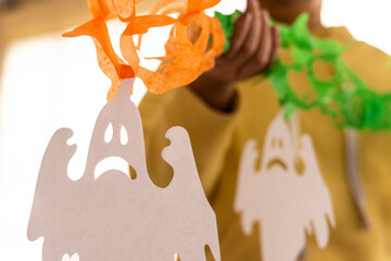 Close-up of vibrant Halloween-themed paper decorations, featuring ghost designs in bright colors, reflecting the festive spirit and creativity of the holiday season.