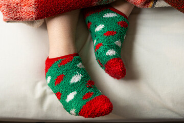 Close up of feet wearing colorful christmas festive socks on bed