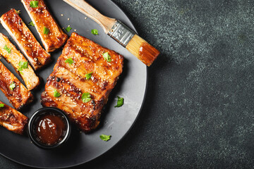Hot grilled spare ribs from a summer BBQ served on a plate with sauce. Top view. Copy space