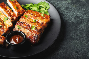 Hot grilled spare ribs from a summer BBQ served on a plate with sauce. Top view. Copy space