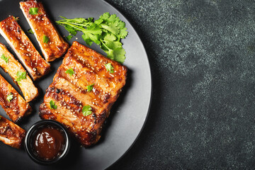 Hot grilled spare ribs from a summer BBQ served on a plate with sauce. Top view. Copy space