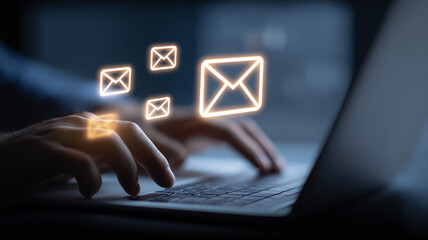 Hands composing messages on a laptop with floating envelopes depict email communication at work, symbolizing outreach, coordination, and efficient digital correspondence.
